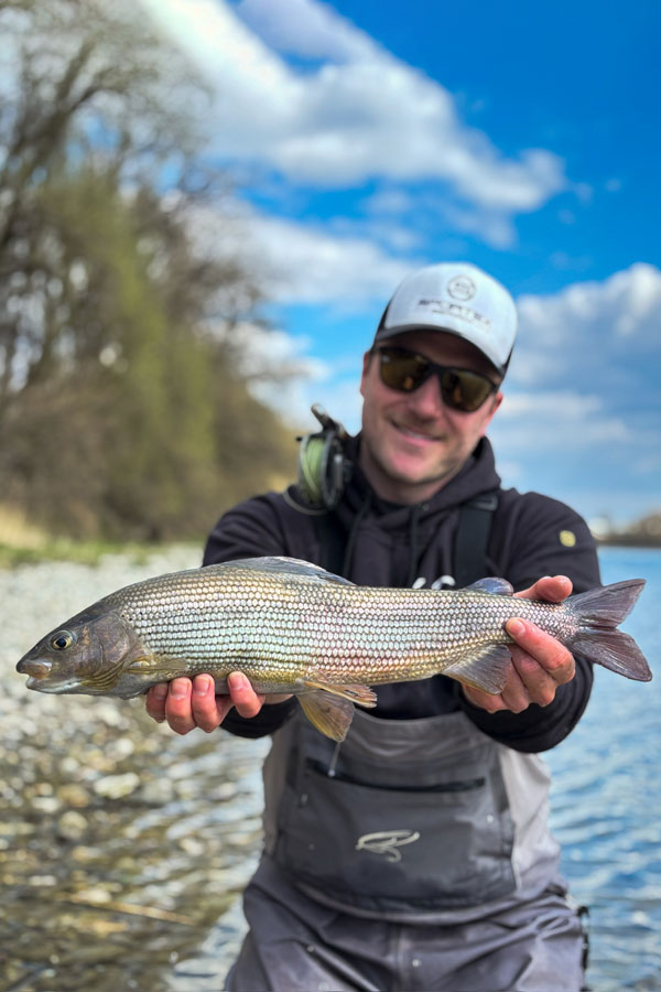 Angler mit Wathose und Fisch