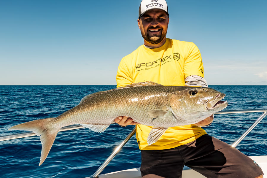 Angler mit Fisch am Meer